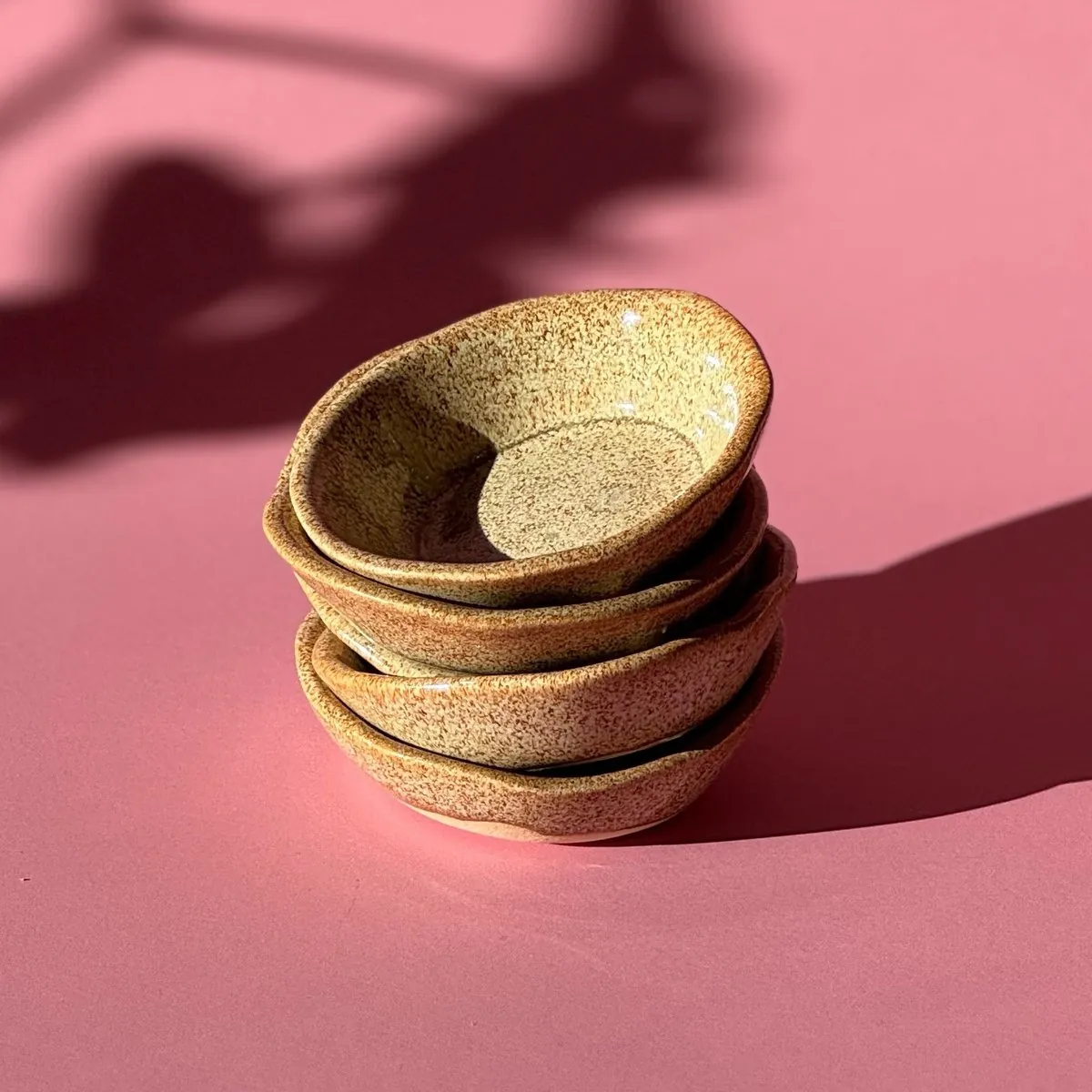 A stack of four little speckled dishes