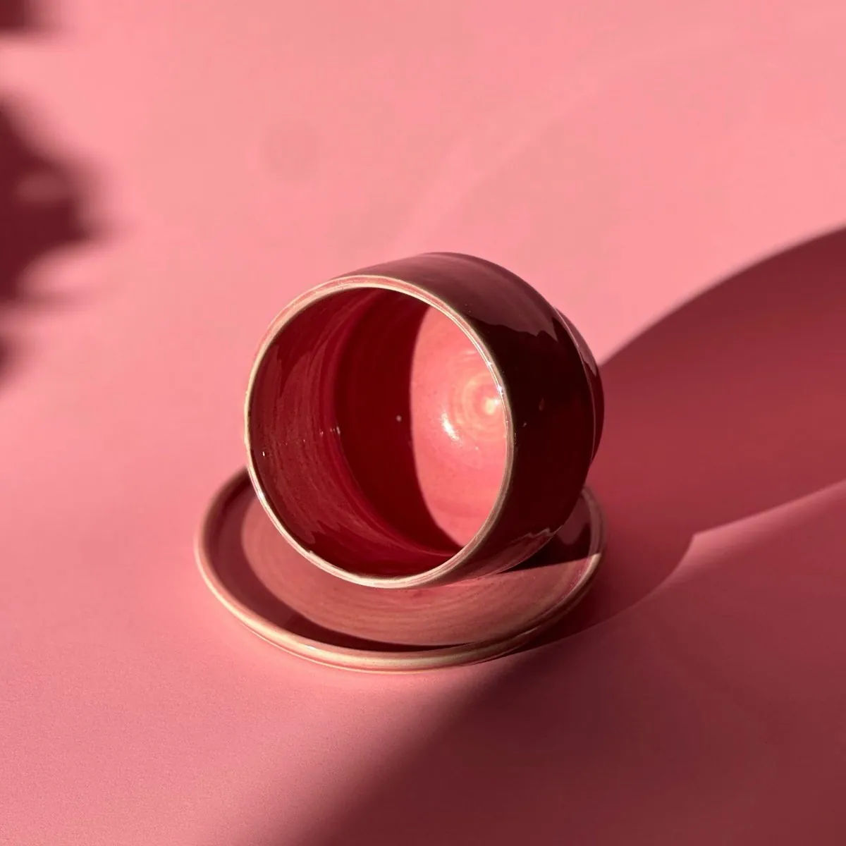 Raspberry cup with a pink interior, tipped on its saucer