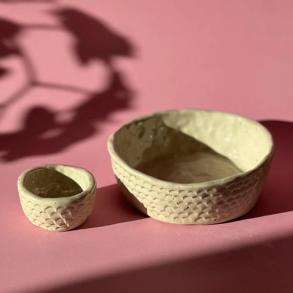 A large and a small cream bowl with a carved scallop pattern
